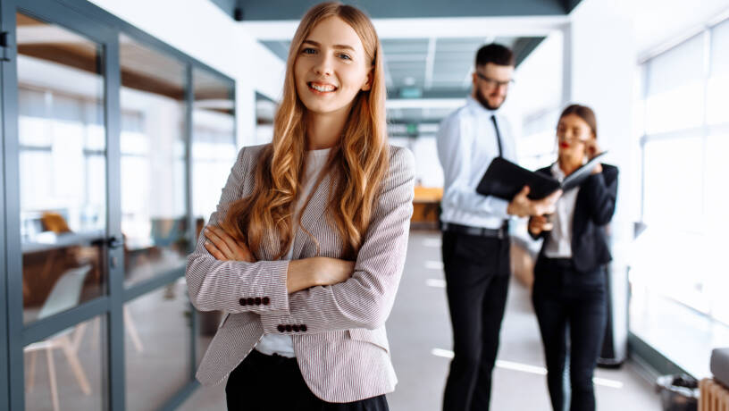 Executive assistant standing confidently in modern office environment
