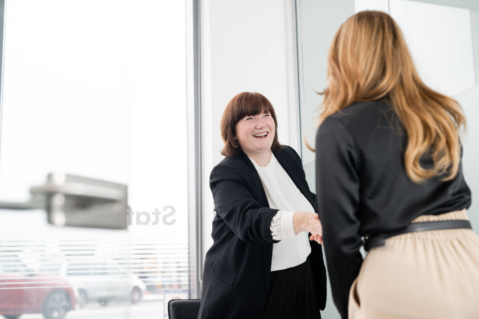 Two women shaking hands and smiling