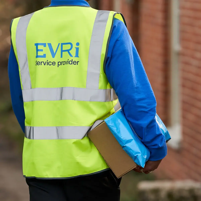 A rear view of an Evri operative wearing a branded high-visibility vest and carrying parcels, representing warehouse and delivery roles available in Mallusk.