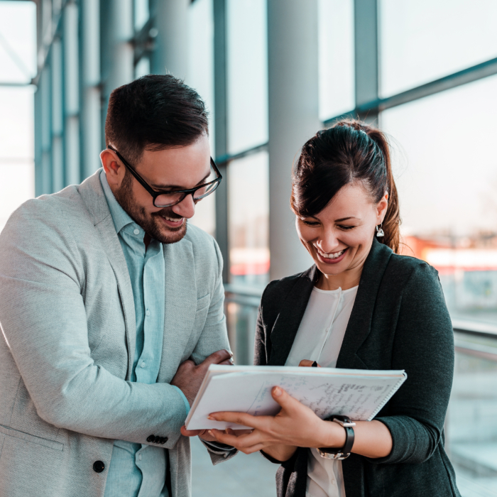 Two colleagues engaged in discussion during a team meeting, highlighting the importance of collaboration and strong organisational culture in attracting and retaining talent in Belfast’s competitive 2026 job market.