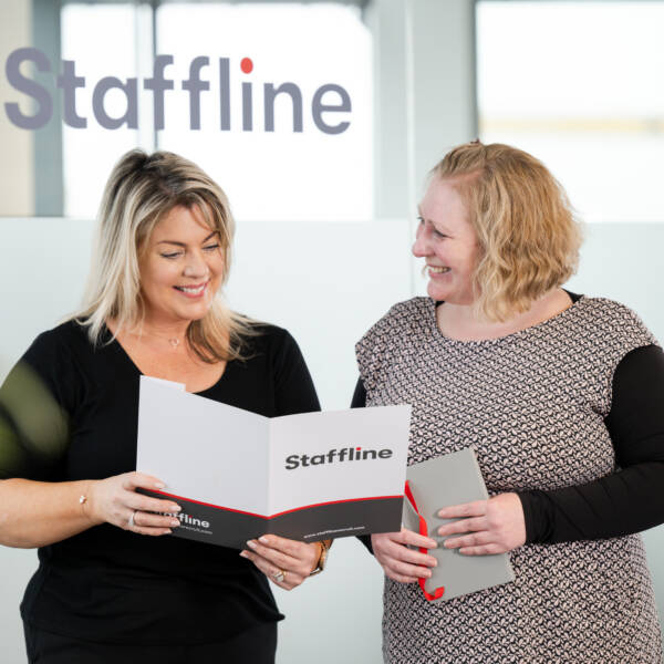 Two women smiling and holding a Staffline booklet