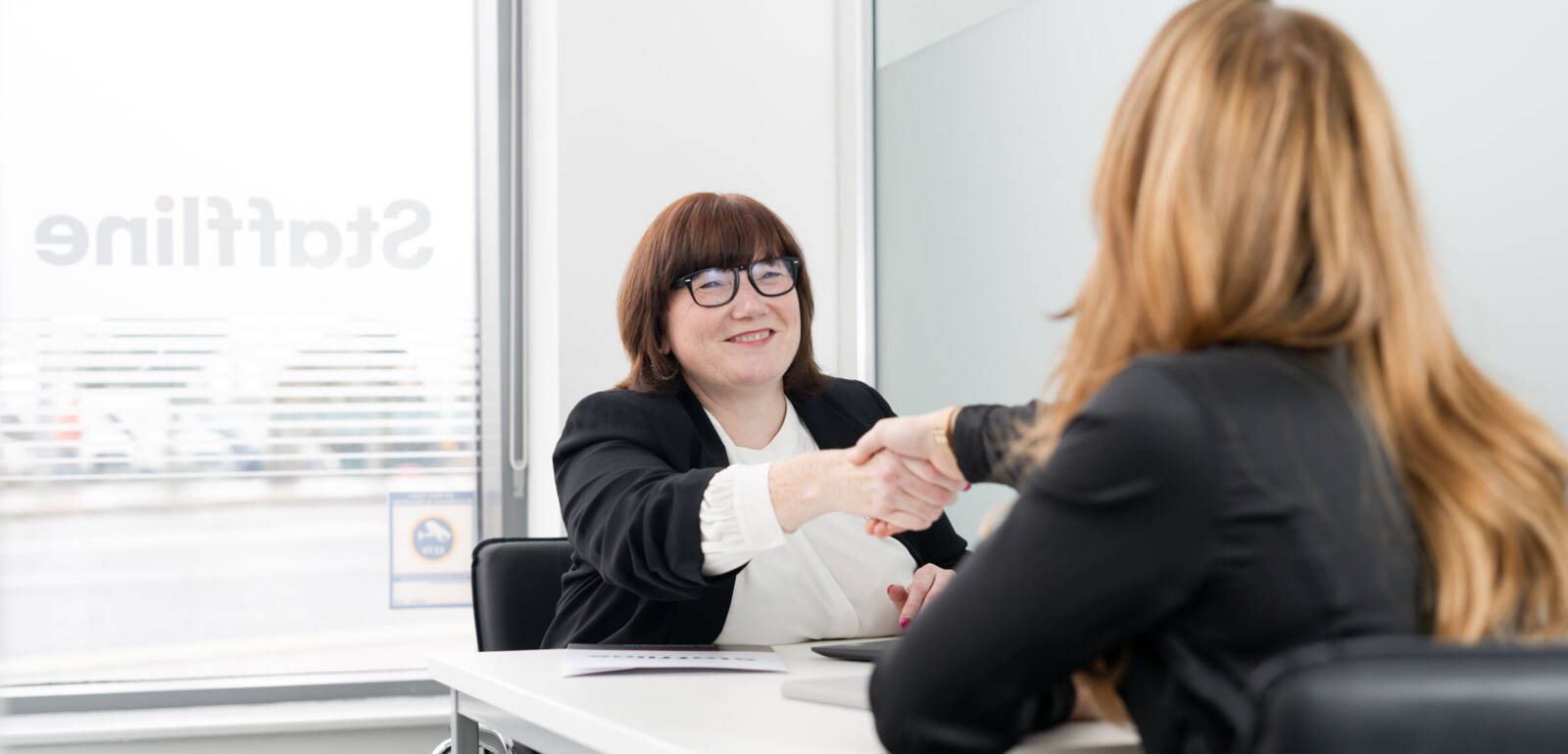 Two women shaking hands in a Staffline office space