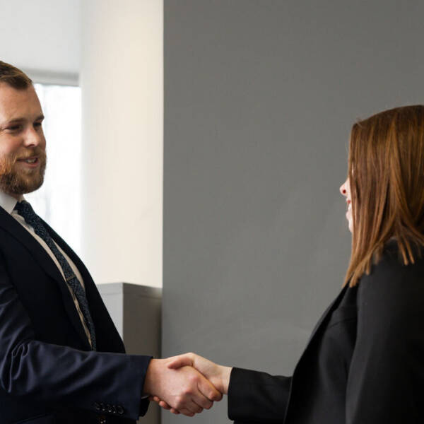 Two people greeting each other with a handshake in front of a Staffline wall sign