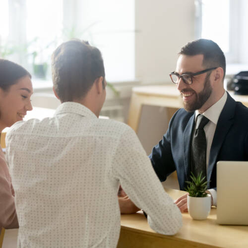 Banking employee smiling and chatting to two customers