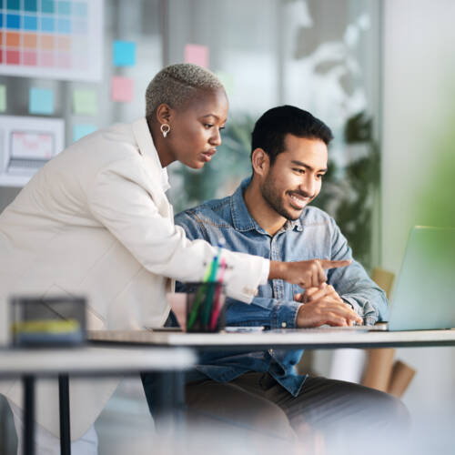 two marketing employees working on laptop together