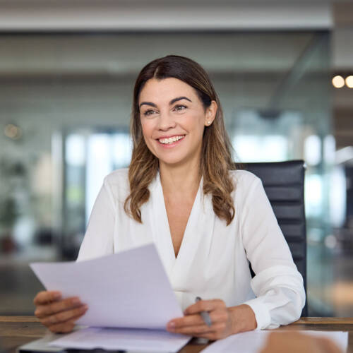 Woman smiling while handling papers at a desk